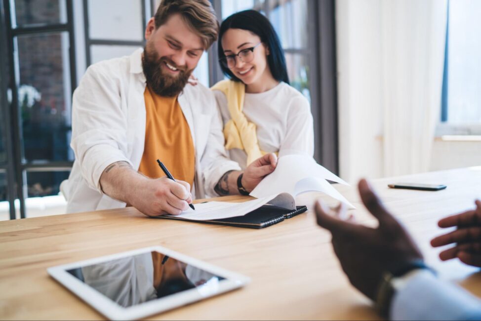 Happy couple signing a signature loan 