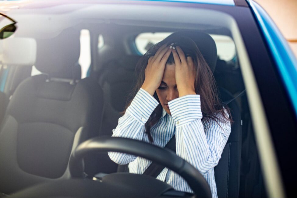 Stressed woman holding her head in a car
