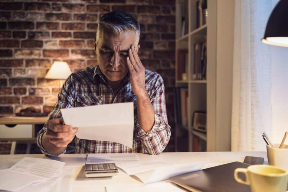 A man is worried while reviewing his personal loan and bills