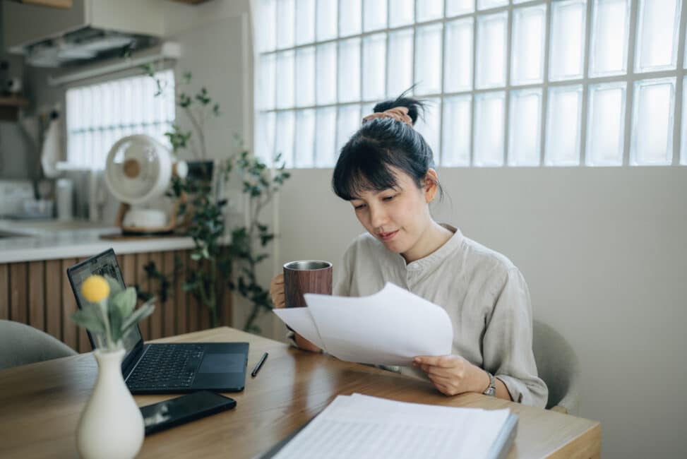 Asian women working with invoices, calculates expenses doing work at home.