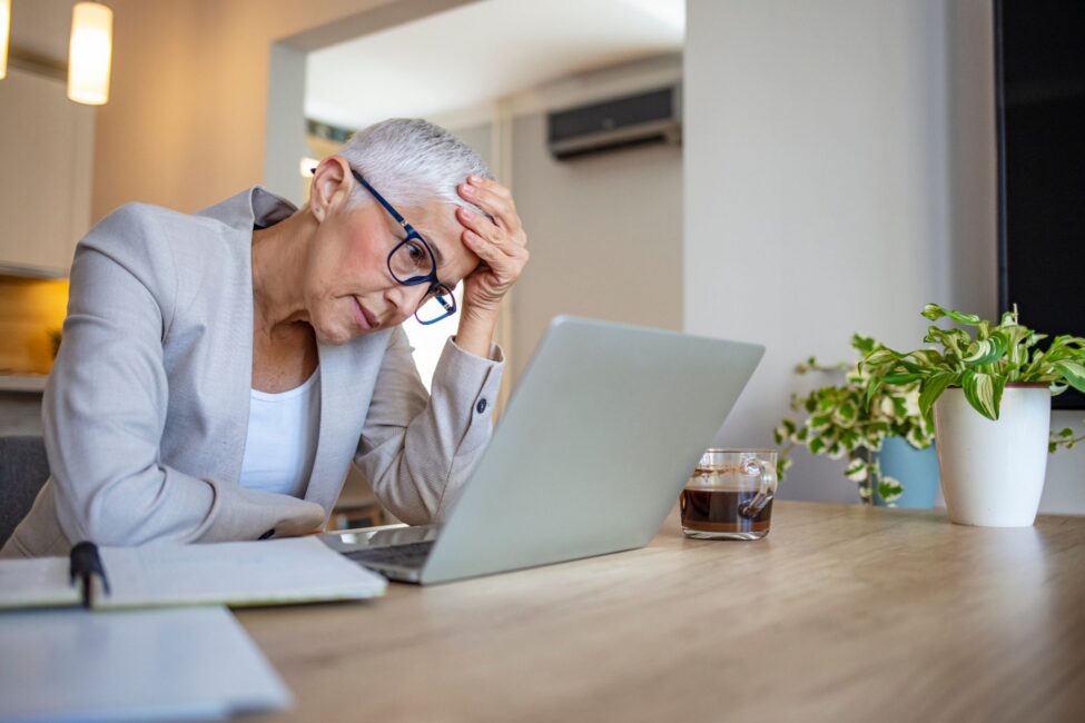 Woman looking at her laptop with a concerned expression as she confronts the consequences of her bad money habits