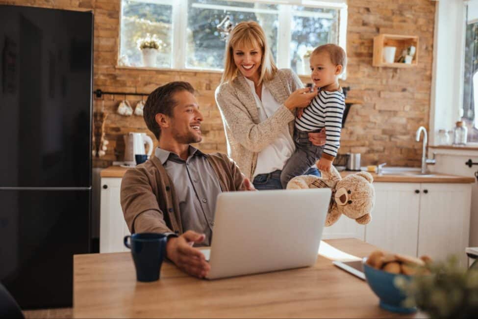 A mother holding a toddler and a father working on a laptop to file their taxes and Child and Dependent Care tax credit