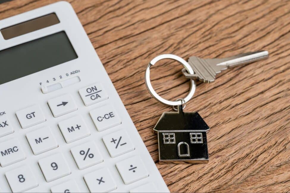 Key with house keyring next to a calculator
