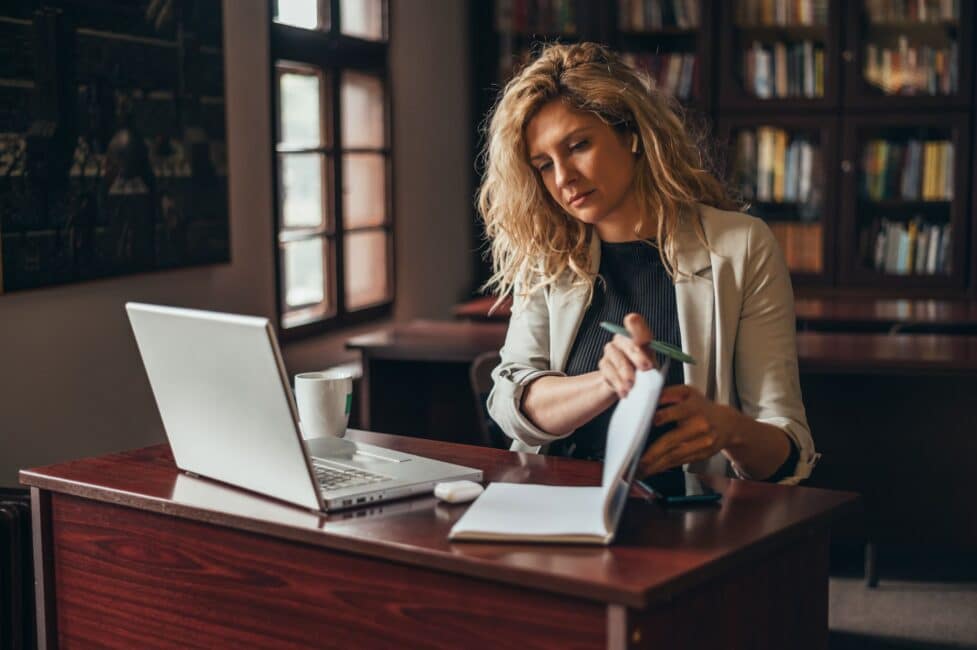 Woman working at her desk with a laptop and notebook to organize financial records