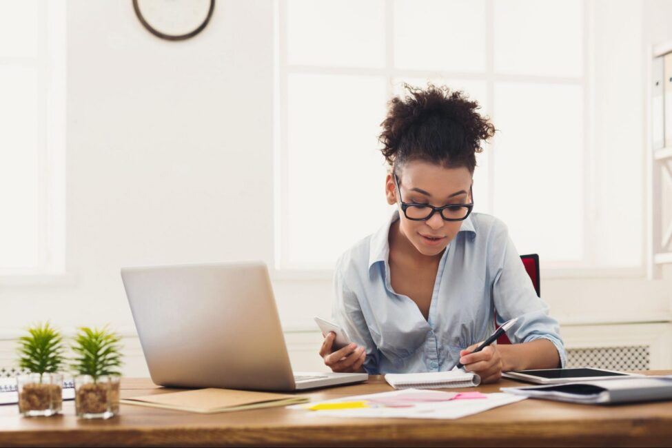 A woman sits at a table to create a guest list for her budget birthday party 