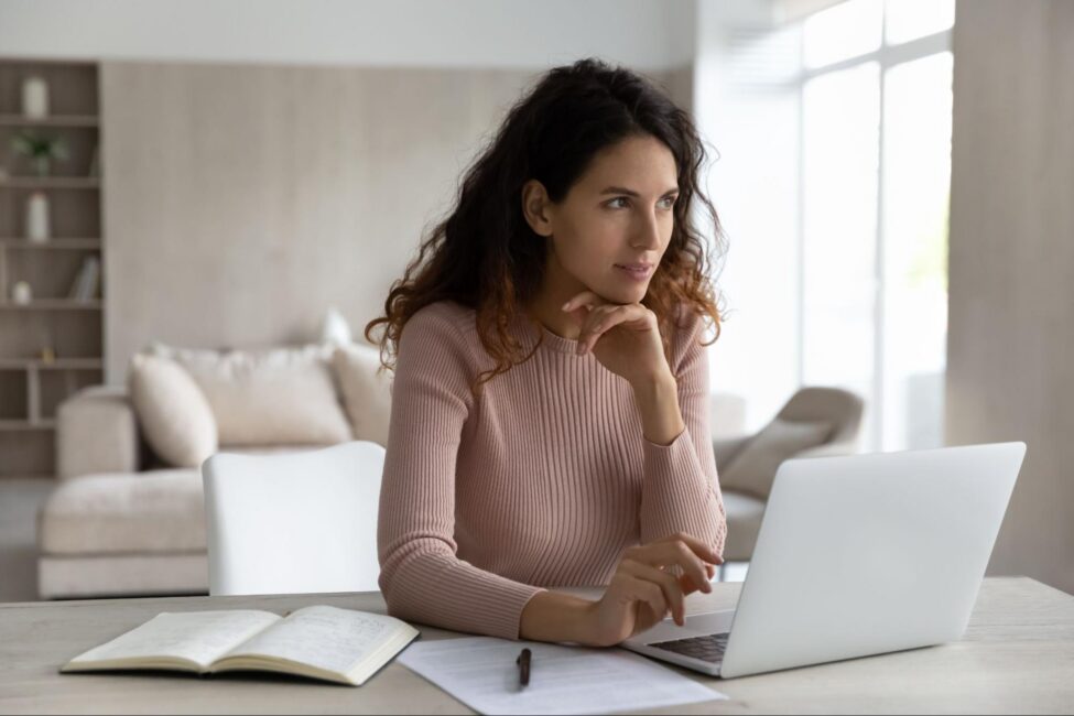 Young woman contemplating an IRA savings account and reviewing documents on a laptop