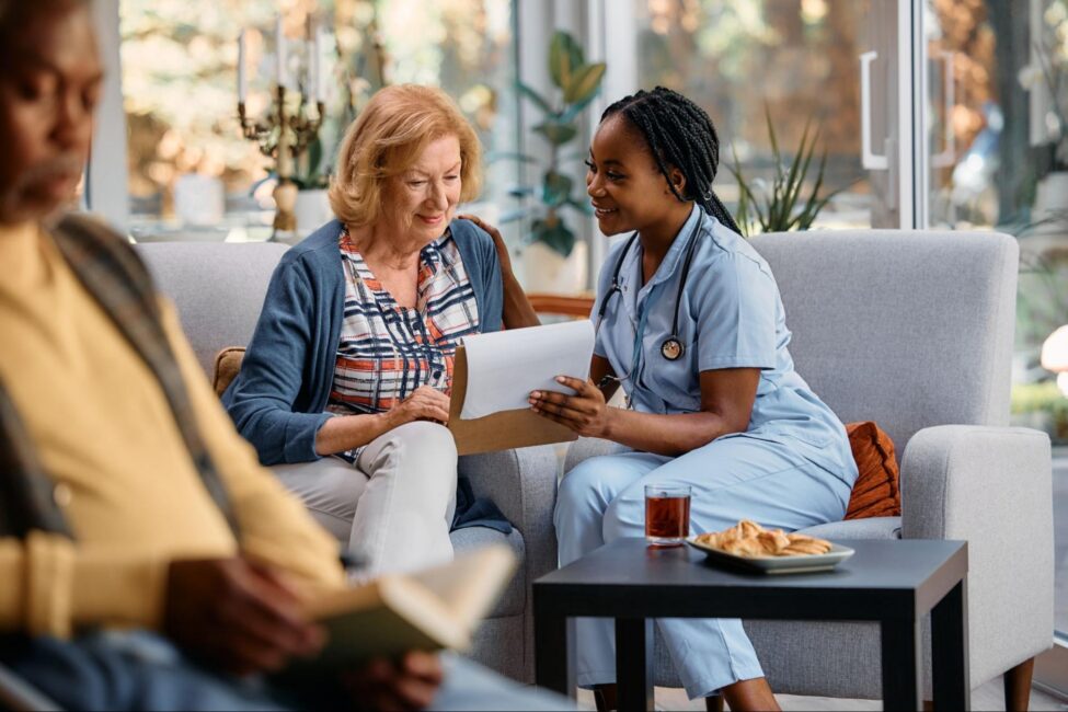 Nurse in blue scrubs reviewing financial assistance documents with a senior woman