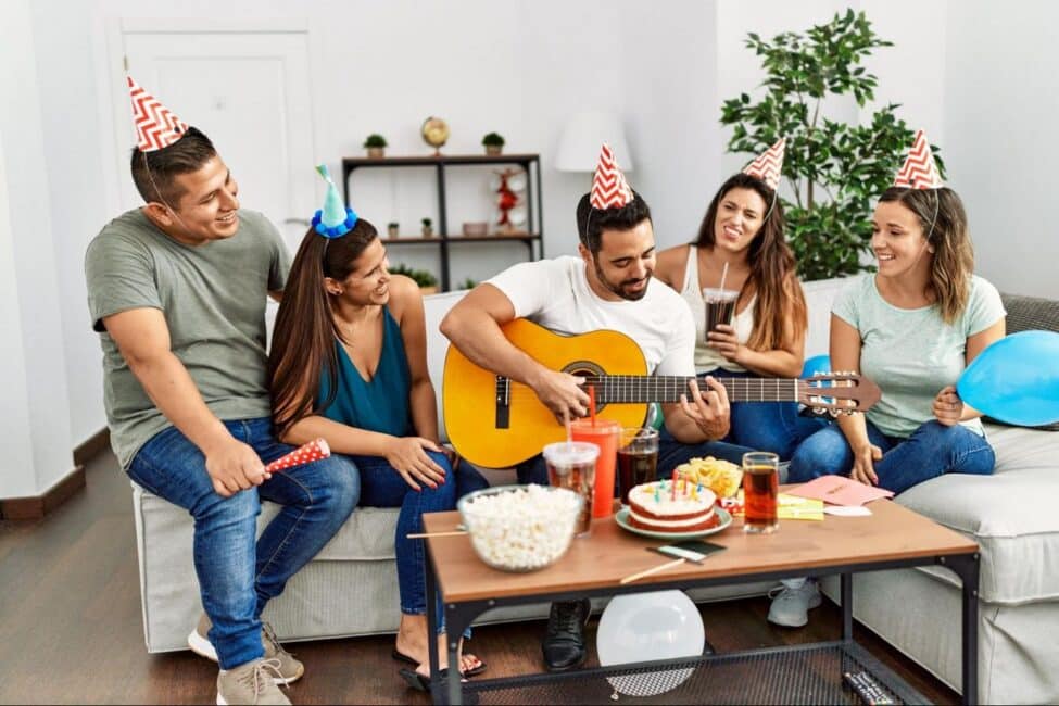 Friends enjoying music together in a living room at a budget birthday party with simple entertainment 