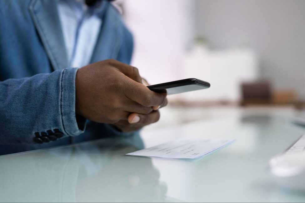 A person using their smartphone to take a photo of a paper check 