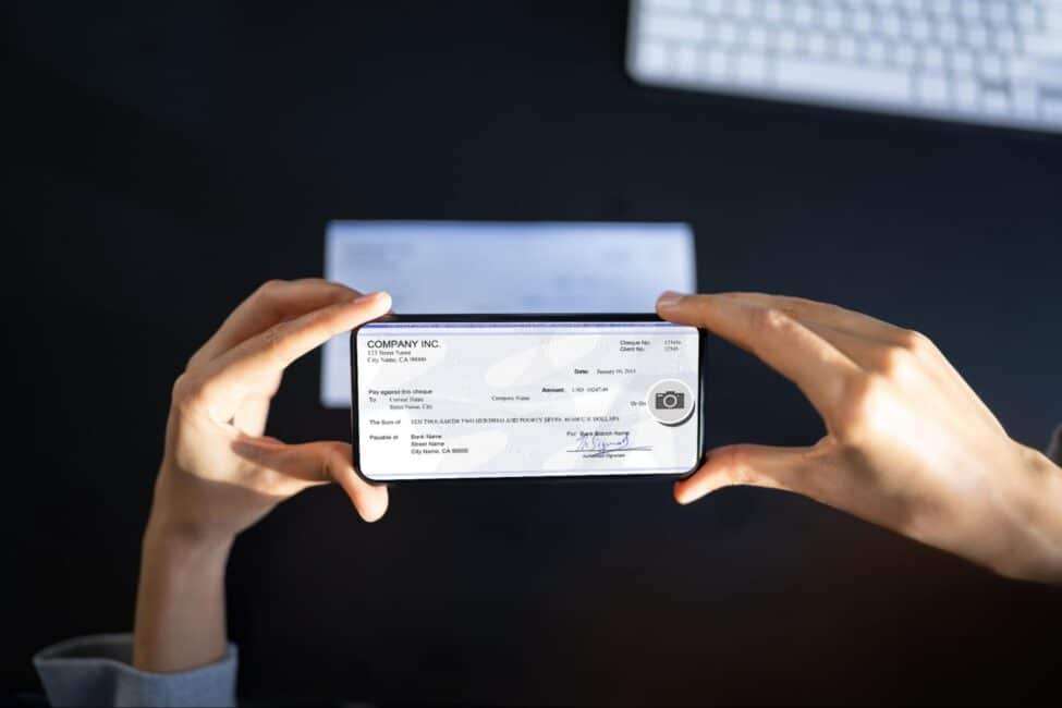 A woman using her smartphone to take a photo of a check for a mobile check deposit