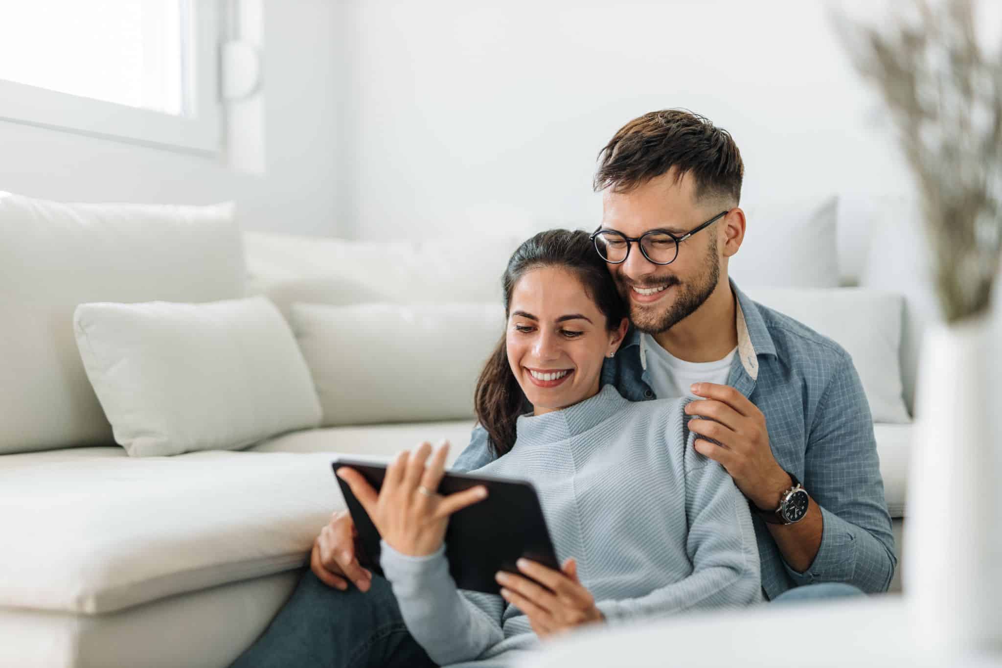 Happy couple at home using a tablet to open a joint bank account online