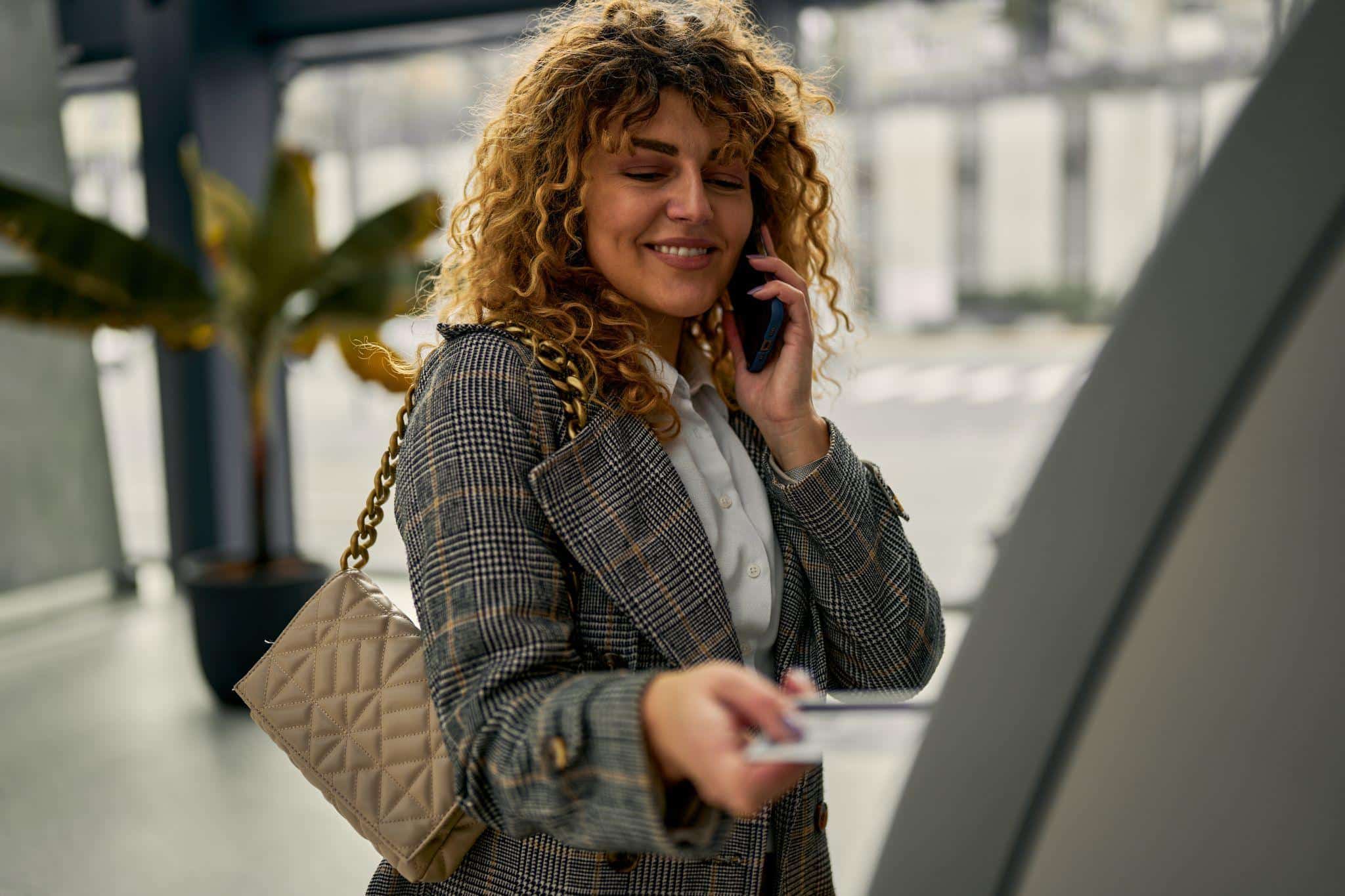 A smiling woman withdrawing funds from an ATM