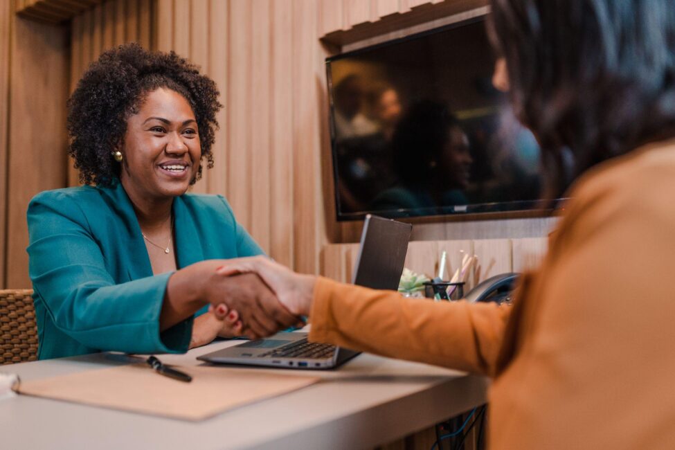 A smiling loan officer shakes hands with a client, confirming they completed all personal loan requirements
