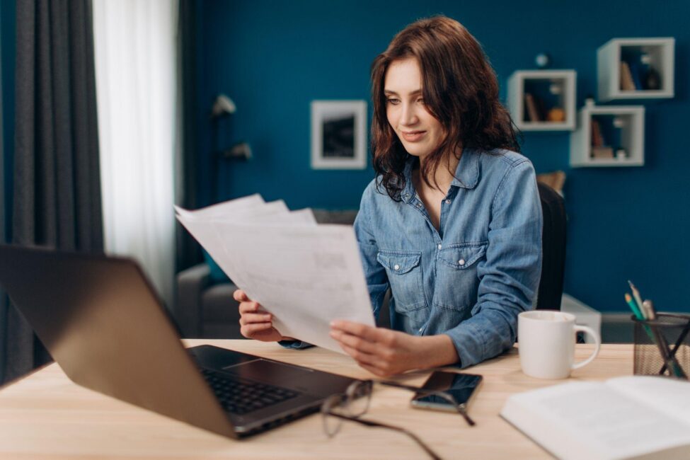 A woman reviews personal loan documents at home with her laptop
