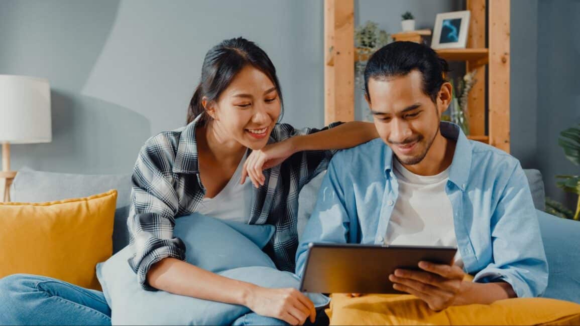 Smiling young couple comparing home improvement loan lenders and rates on a tablet