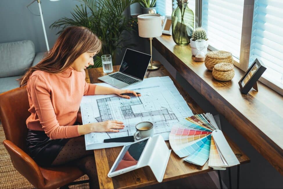 Woman sitting at a desk reviewing blueprints as she plans a home improvement project
