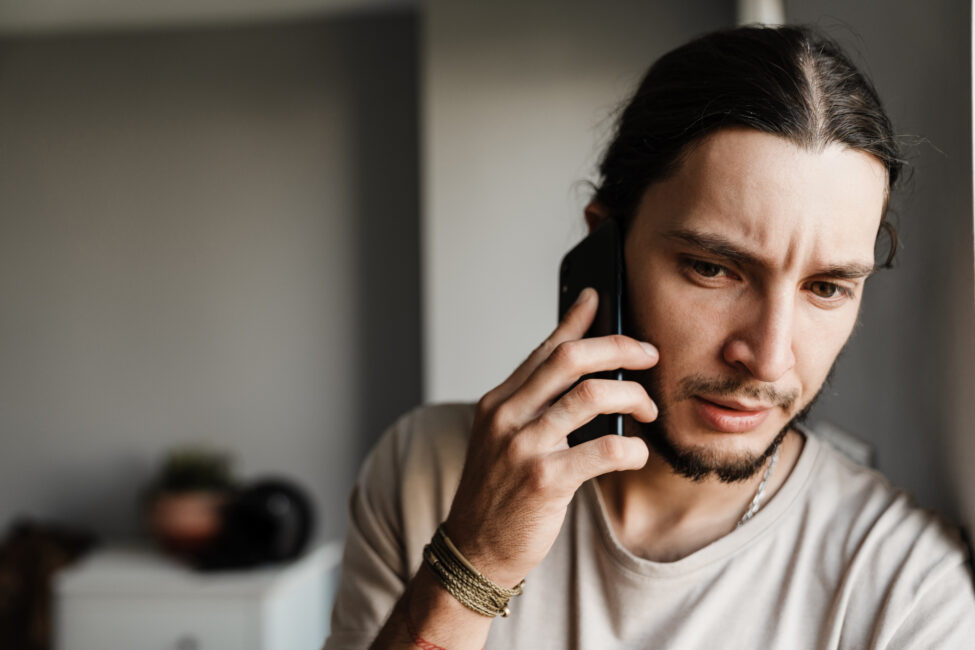 Concerned man talking on a phone, looking for emergency rent help